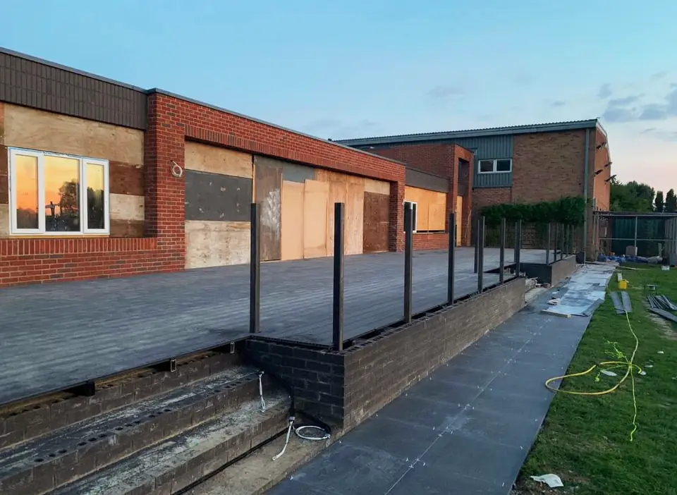 Completed raised decking beside a brick building at dusk, London project