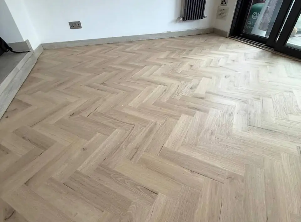 Light oak-effect herringbone floor in an empty room