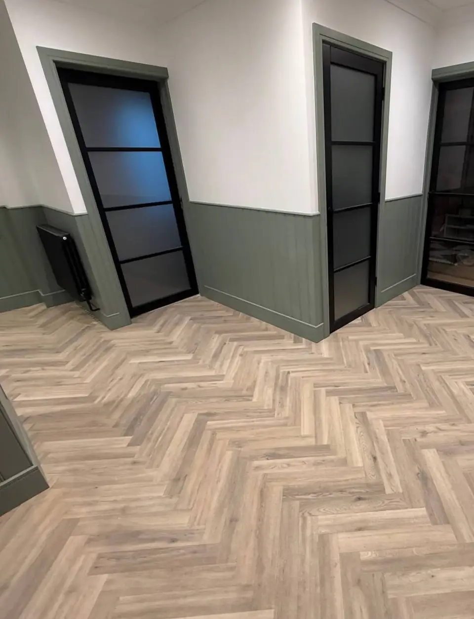 Black glazed internal doors with green panelling and a herringbone floor