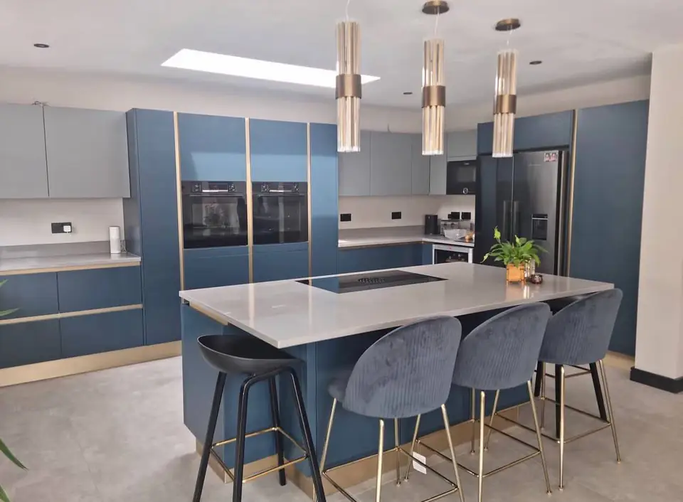 Navy kitchen with a quartz-topped island, three brass pendant lights and grey bar stools