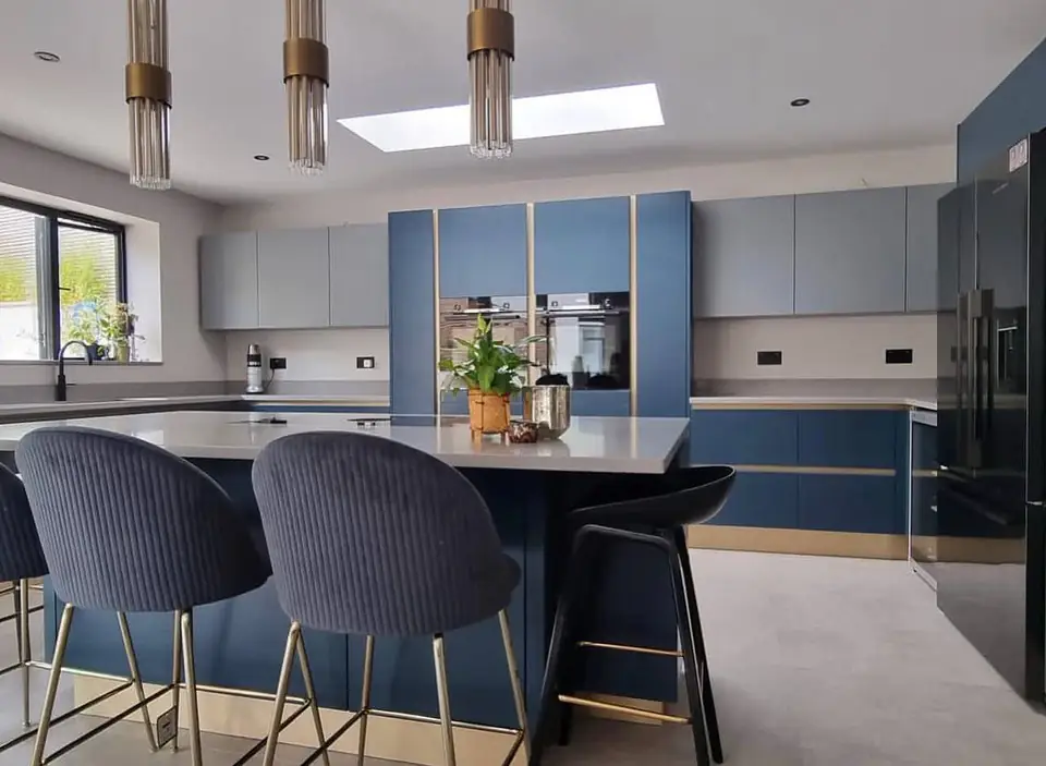 Navy island with velvet bar stools in front of tall navy units and built-in ovens