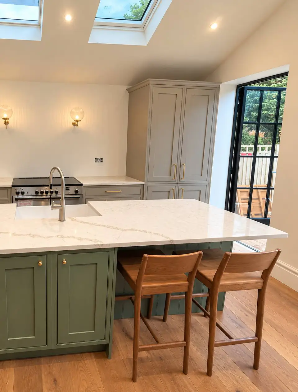 Island with a marble-effect worktop, sink and two timber bar stools, black glazed door behind