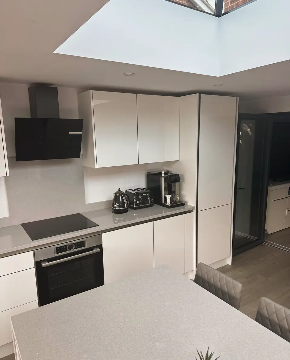 White gloss kitchen with a grey worktop under a roof lantern