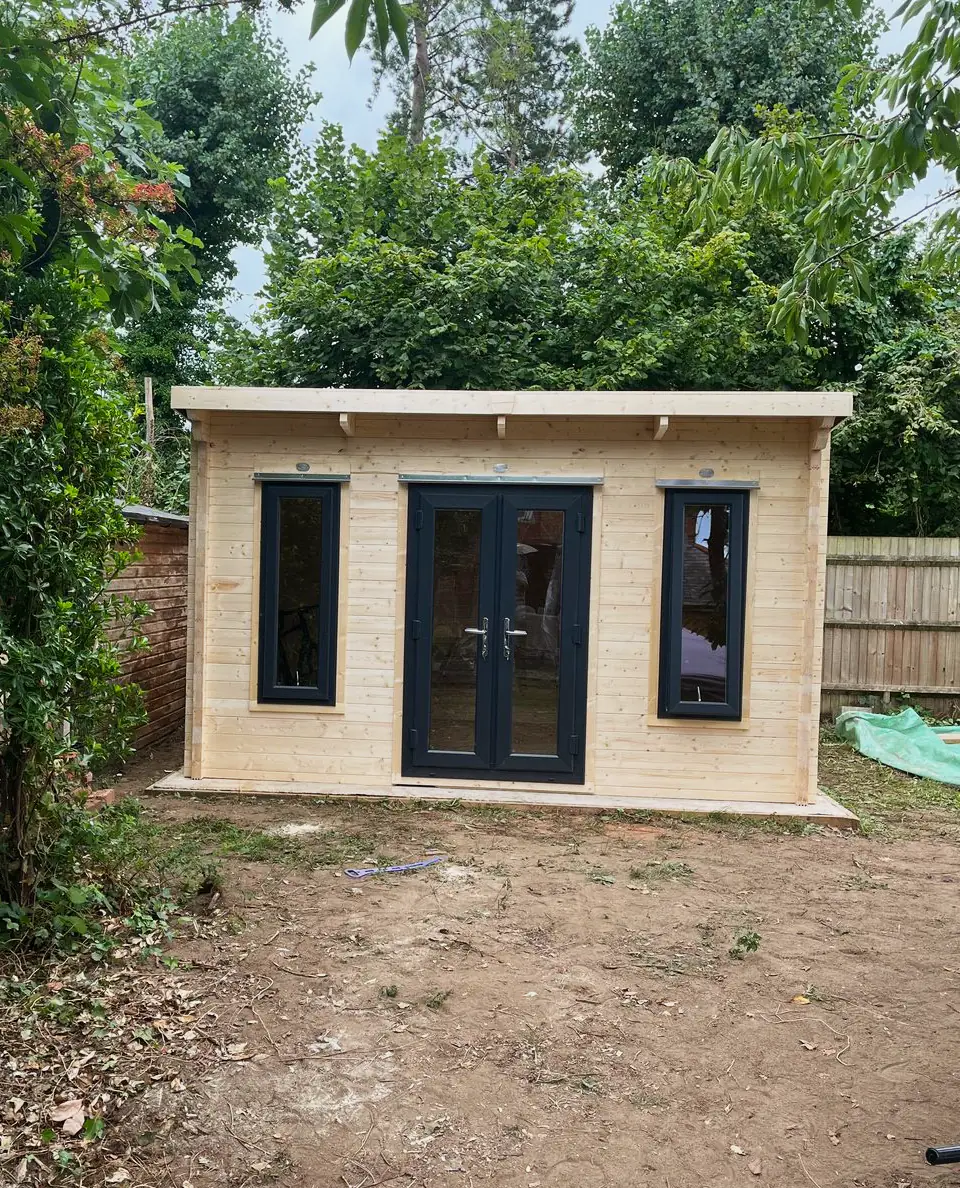 Timber garden building with dark French doors and two tall windows