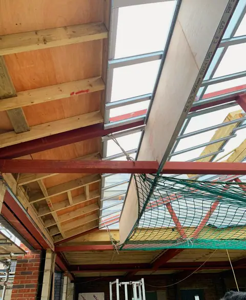 Steel beams supporting a timber roof with skylights, London project
